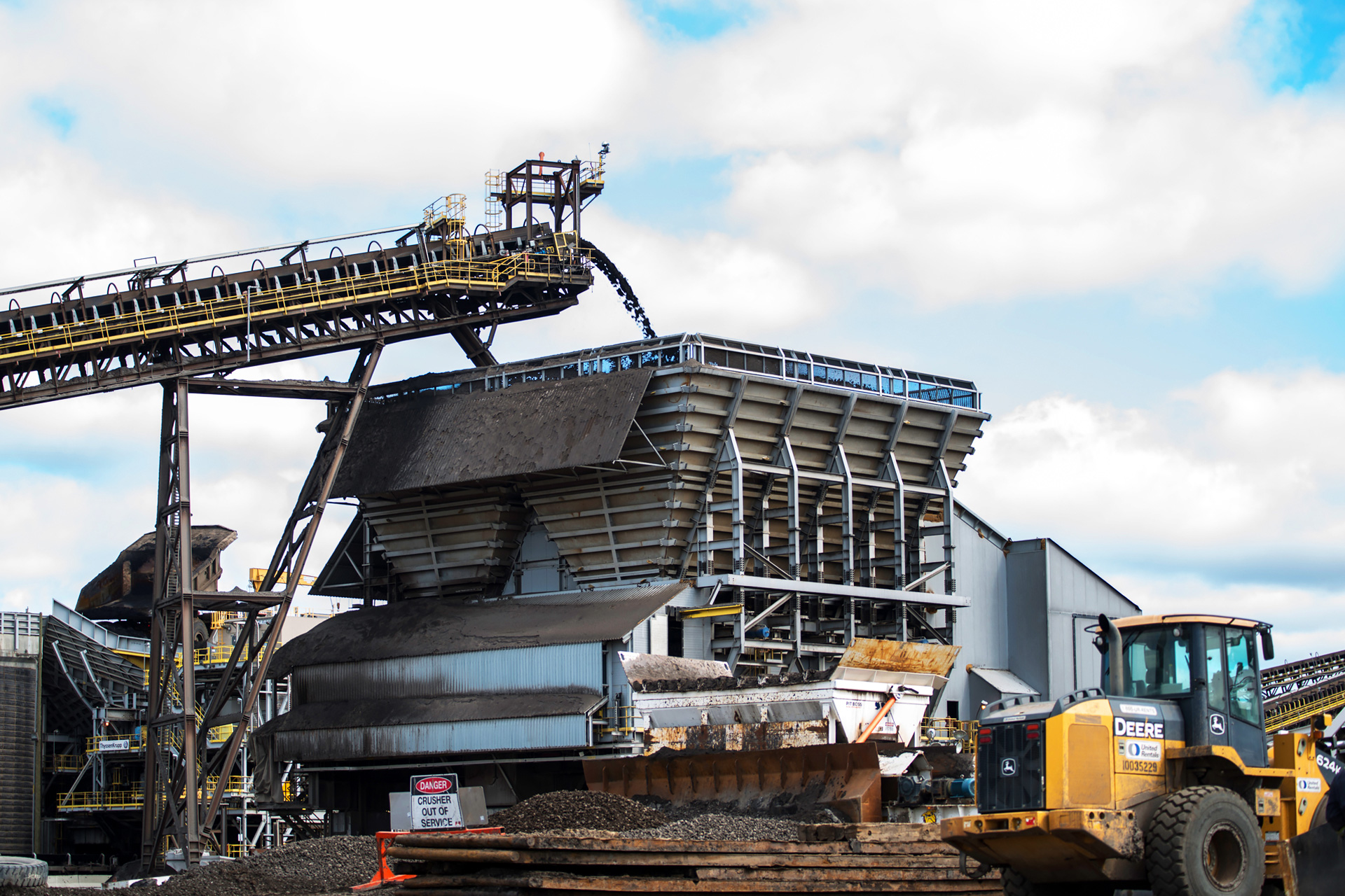 oil sands travel up a conveyor belt into a surge bin