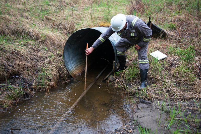 Inspector measures the depth of the pool at the mouth of the culvert