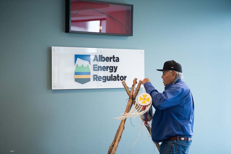 Blackfoot Elder Dr. Reg Crow Shoe places the AER’s bundle on its birch pole stand