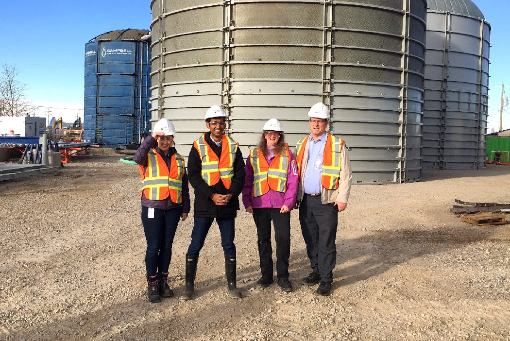 Alberta Energy Regulator staff pose near a reusable-bladder tank 